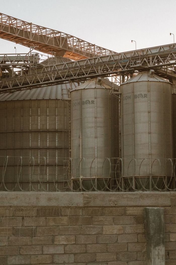 Crafting Captivating Headlines: Your awesome post title goes here A view of large metal grain silos under clear evening skies with industrial infrastructure.